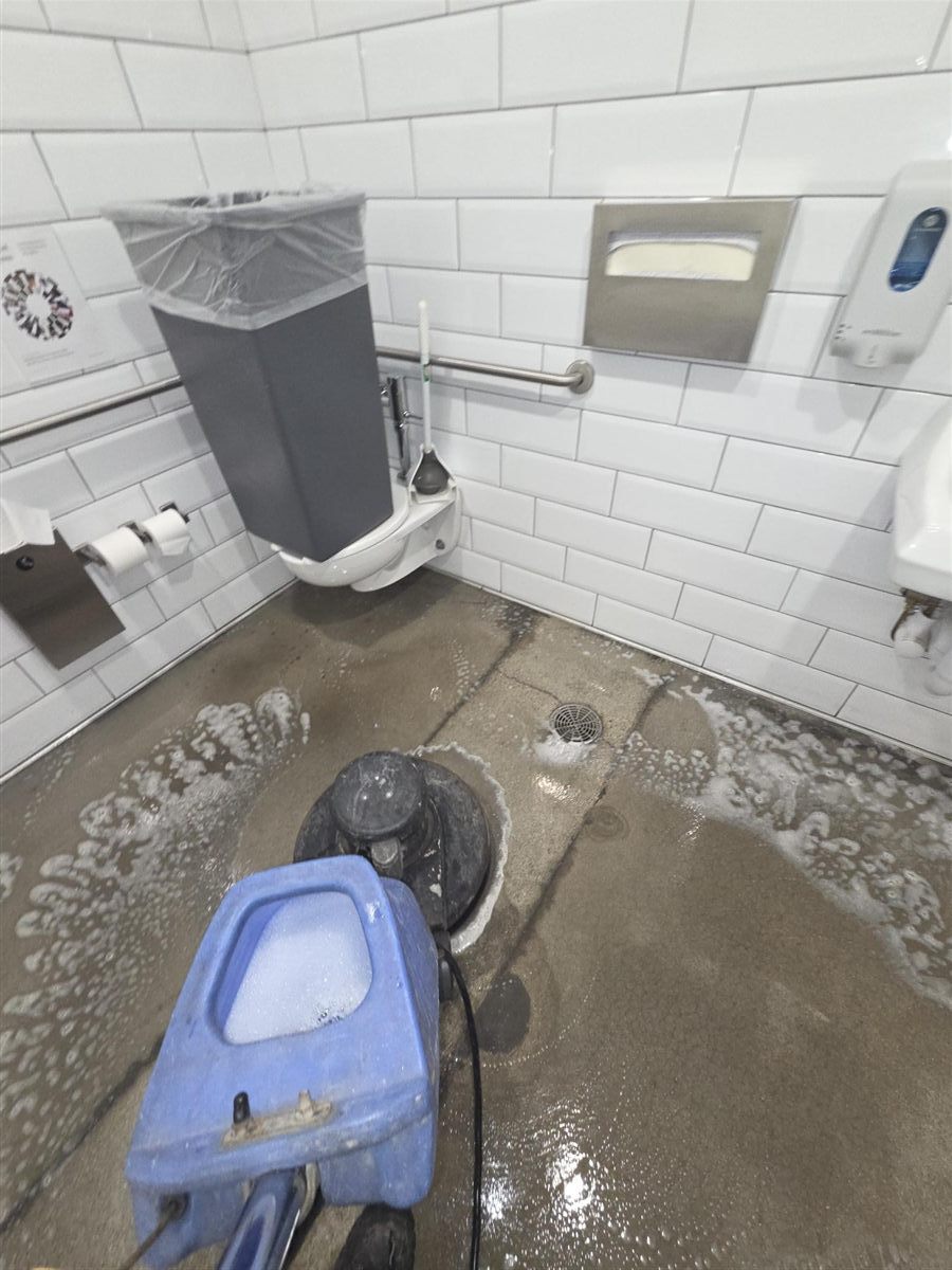 Done Just Right janitorial technician machine scrubbing a commercial restroom floor